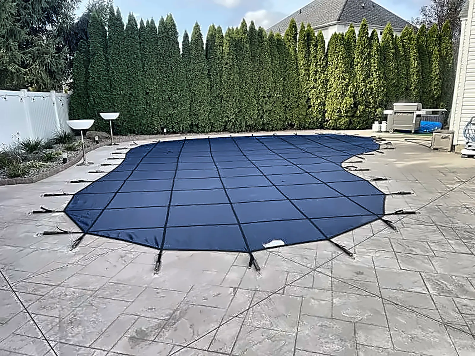 Home 7 Black safety cover secured over a closed in-ground pool