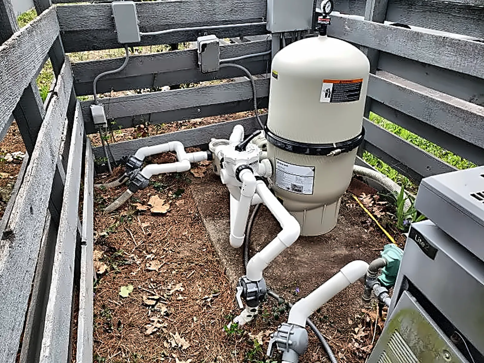 Home 12 Pool filter and plumbing equipment installed beside a backyard fence