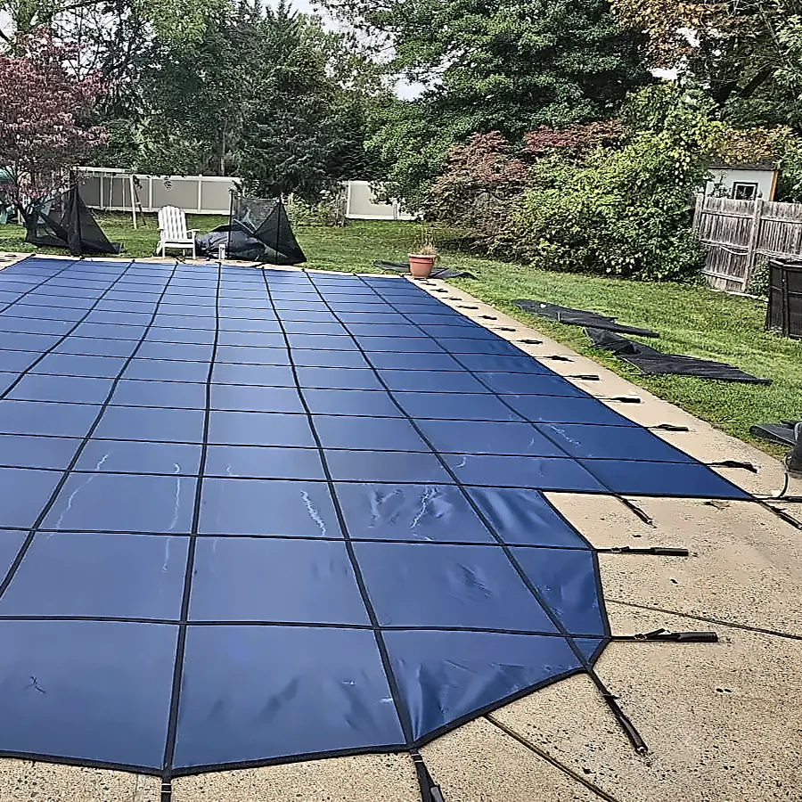 Safety cover straps anchored around a closed in-ground pool