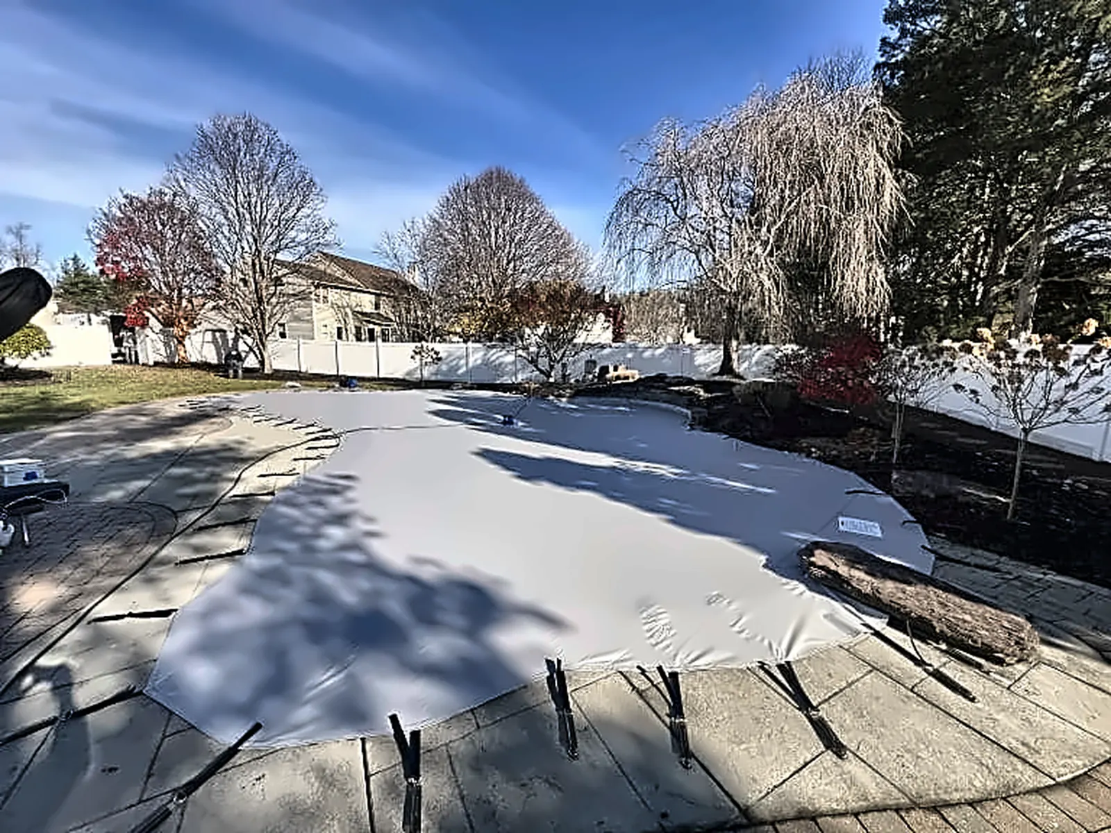 Snow-covered safety cover secured over a closed residential pool