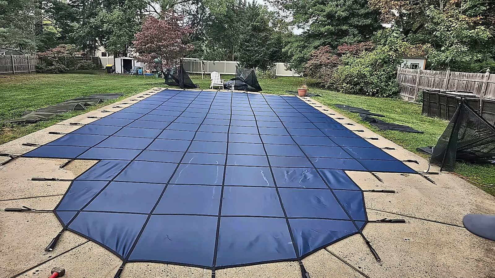 Home 11 Blue safety cover secured over an in-ground backyard pool